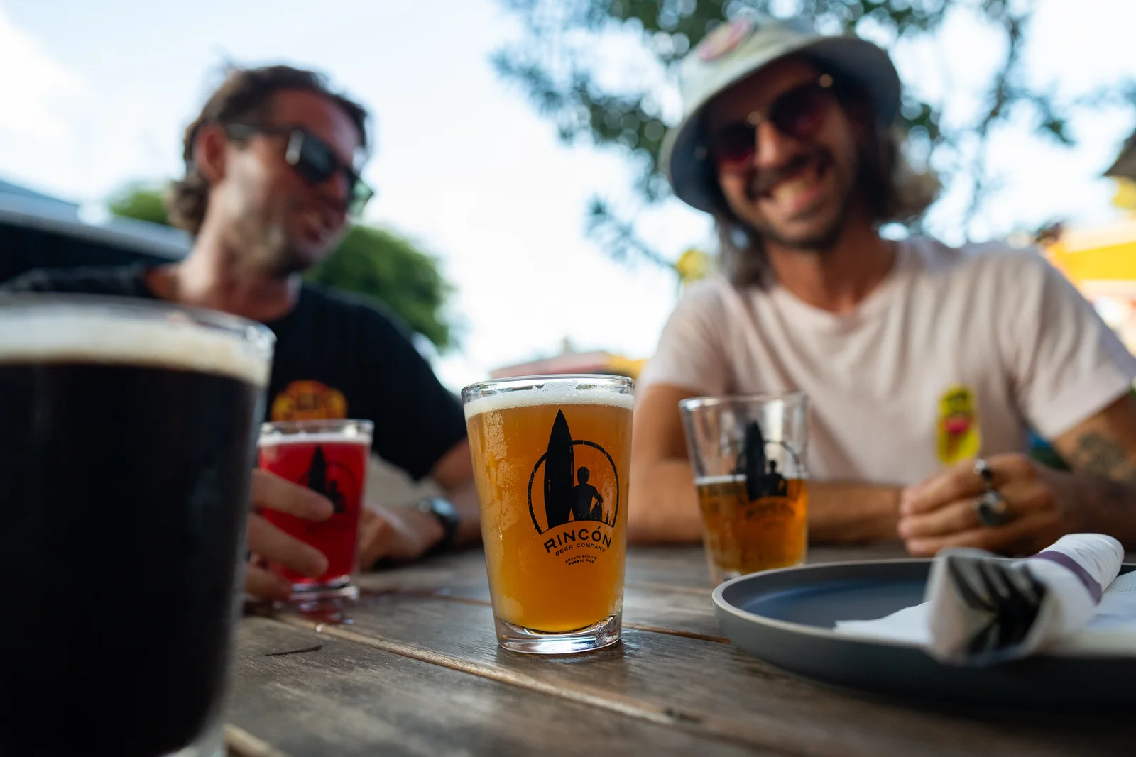 Amigos brindando con vasos Rincón Beer Company al aire libre durante un evento privado